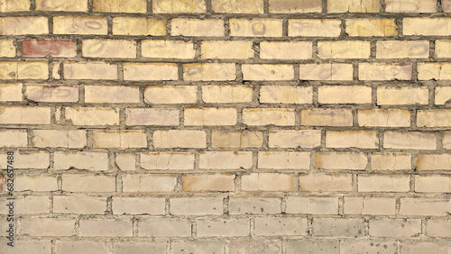 The wall is made of light ochre brown scuffed brick. Old dilapidated brick masonry.