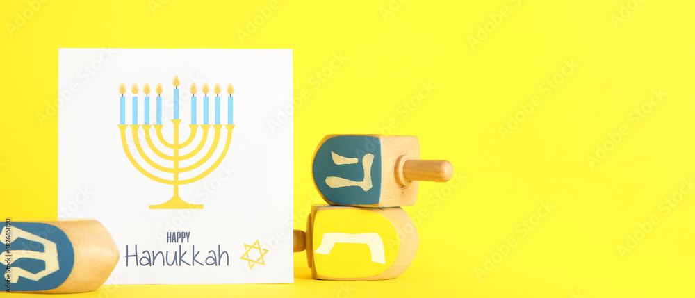 Dreidels with greeting card on yellow background with space for text. Hanukkah celebration Dreidels with greeting card on yellow background with space for text. Hanukkah celebration