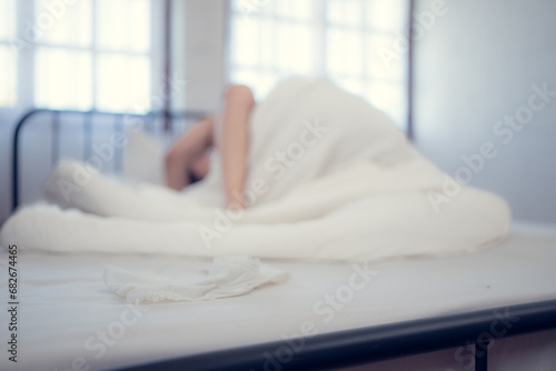 Blurred image of young man and woman lying on the bed in the bedroom with women's underwear in the foreground