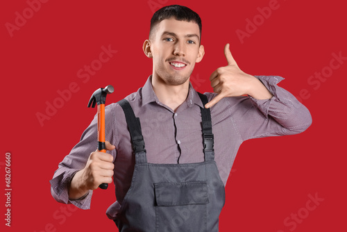 Male builder with hammer showing "call me" gesture on red background