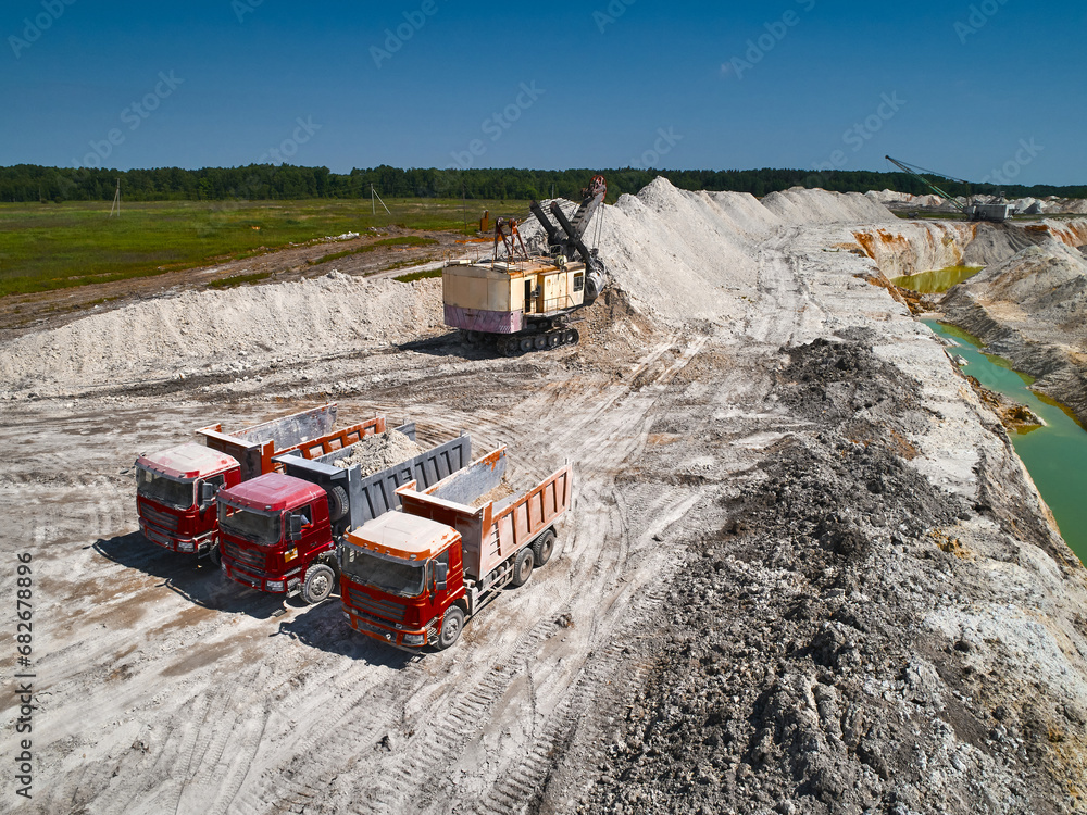 Red tipper trucks and shovel mining excavator in mining quarry Red tipper trucks and shovel mining excavator in mining quarry