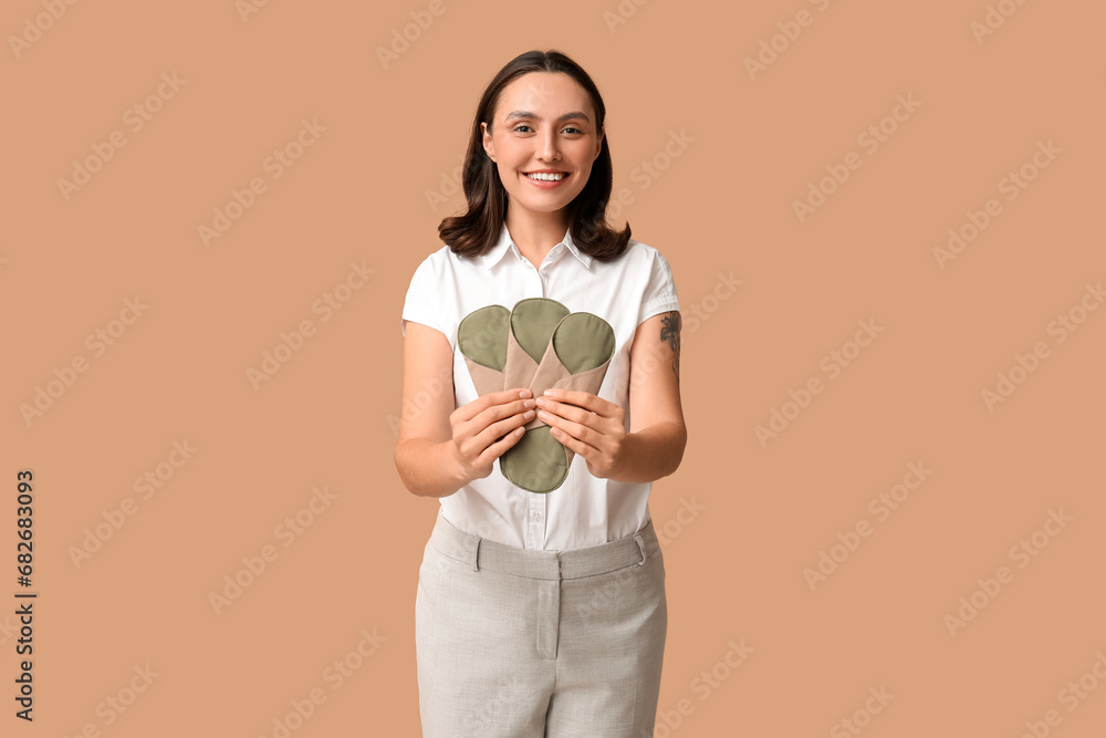 Beautiful young woman with reusable menstrual pads on brown background Beautiful young woman with reusable menstrual pads on brown background