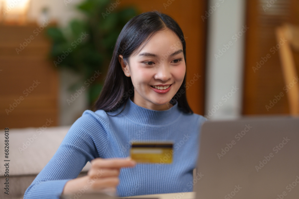 Young asian woman using laptop computer and credit card for online shopping at home. Asia female enjoying the convenience of online shopping from the comfort of her home. Young asian woman using laptop computer and credit card for online shopping at home. Asia female enjoying the convenience of online shopping from the comfort of her home.