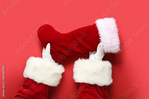 Santa hands with Christmas sock on red background, closeup