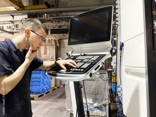 Obraz na płótnie Pensive and inexperienced worker looking for the right button on a cnc milling m