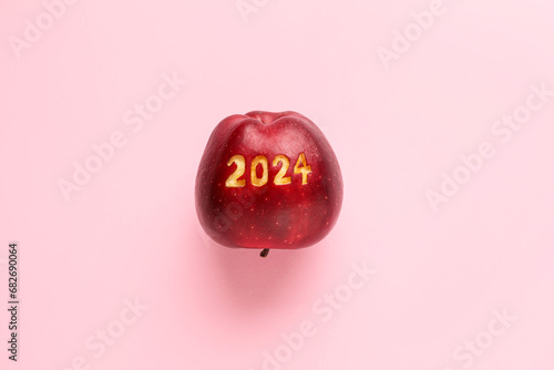 Ripe apple with with carved figure 2024 on pink background photo