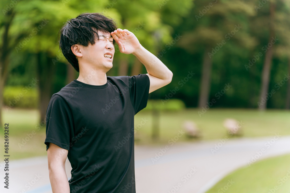 公園で運動して深呼吸する男性・スポーツマン（運動不足）
