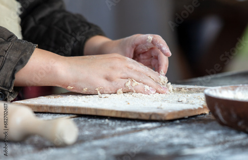 A woman kneads the dough with her hands