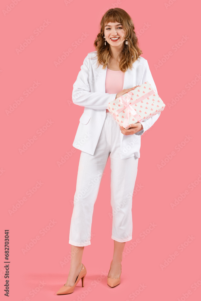 Beautiful young woman with gift box on pink background Beautiful young woman with gift box on pink background