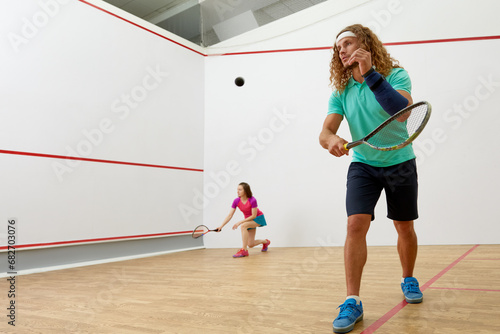 Happy millennial-age couple characters playing game of racquetball together