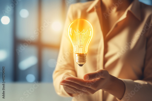 A close-up of a woman's hands holding a glowing light bulb. Convey the concept of new ideas, innovation, and creativity in the workplace.