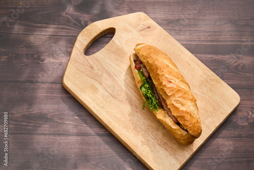 Banh Mi Heo Quay.Vietnamese bread with roasted pork and fresh herbs as scallions, coriander, carrot, cucumber, chilli