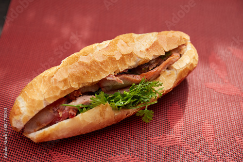 Banh Mi Heo Quay.Vietnamese bread with roasted pork and fresh herbs as scallions, coriander, carrot, cucumber, chilli