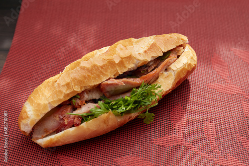 Banh Mi Heo Quay.Vietnamese bread with roasted pork and fresh herbs as scallions, coriander, carrot, cucumber, chilli