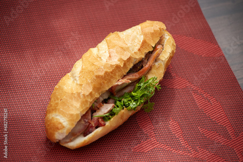 Banh Mi Heo Quay.Vietnamese bread with roasted pork and fresh herbs as scallions, coriander, carrot, cucumber, chilli