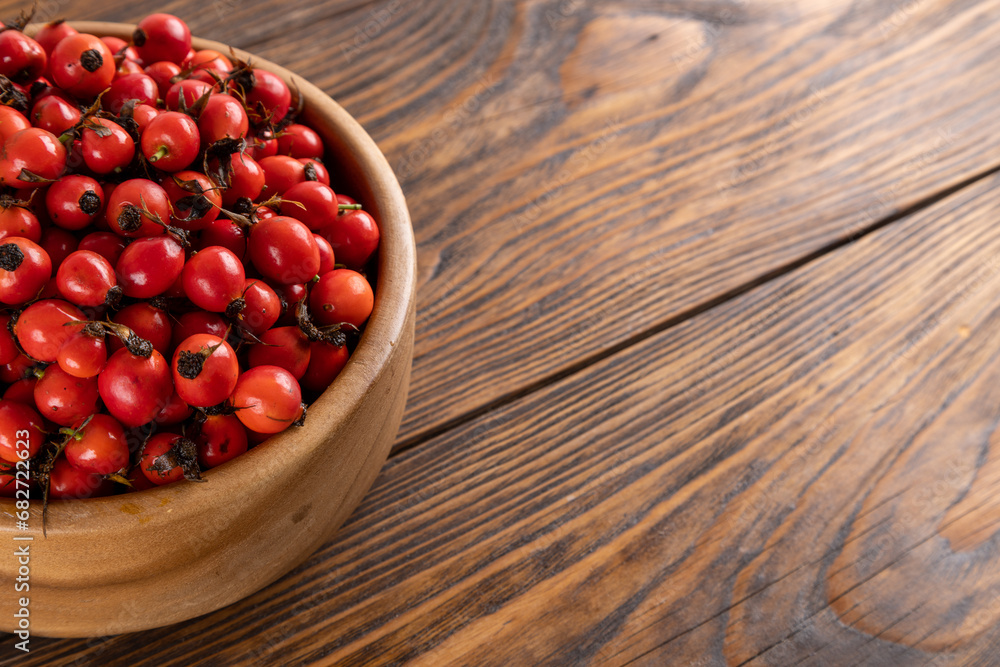 red dog-rose rosehip fruits in a wooden bowl on wooden table red dog-rose rosehip fruits in a wooden bowl on wooden table