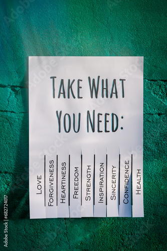 White tear-off stub note with text 'Take what you need' on emerald wall.