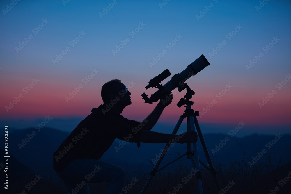 Astronomer looking at the night sky with a telescope.