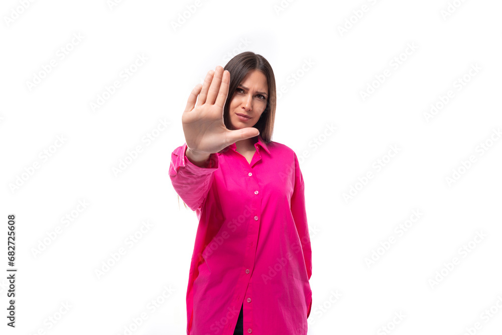 pretty young brunette woman in a bright pink shirt has doubts on a white background with copy space pretty young brunette woman in a bright pink shirt has doubts on a white background with copy space