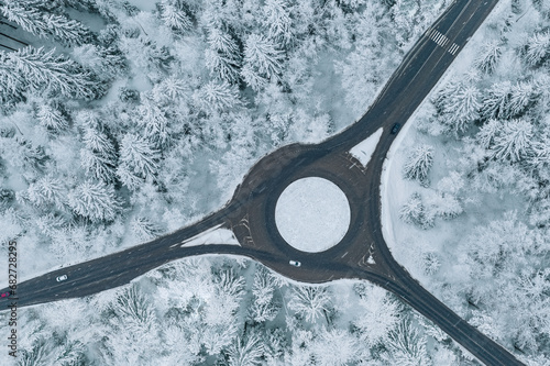 Aerial view of a traffic roundabout and road junctions in snow winter forest