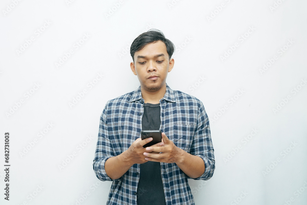 Portrait of Indonesian Asian man smiling when holding smartphone. Isolated white background Portrait of Indonesian Asian man smiling when holding smartphone. Isolated white background