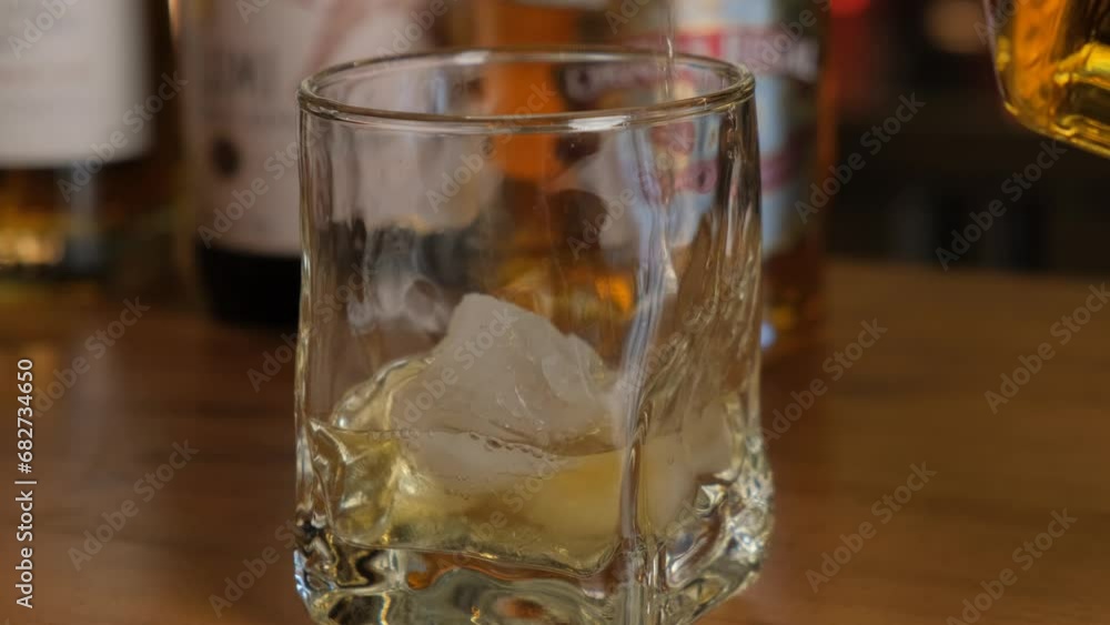Glass of whiskey with ice on a wooden table close-up. Glass of whiskey with ice on a wooden table close-up.