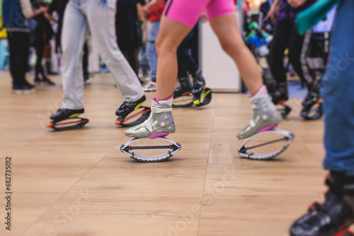 Kangoo shoes, fitness jumping training, group of young fit women in sportswear on kangoo jumps, girls training with coach instructor, exercising at the gym with jump foot wear shoes, fitness studio © tsuguliev