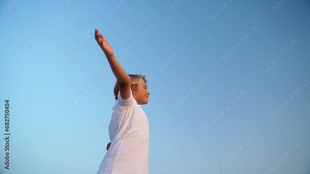 Relaxed teen boy breathing fresh air raising arms over blue sky sunset twilight at summer. Dreaming, freedom and traveling concept. Relaxed teen boy breathing fresh air raising arms over blue sky sunset twilight at summer. Dreaming, freedom and traveling concept.