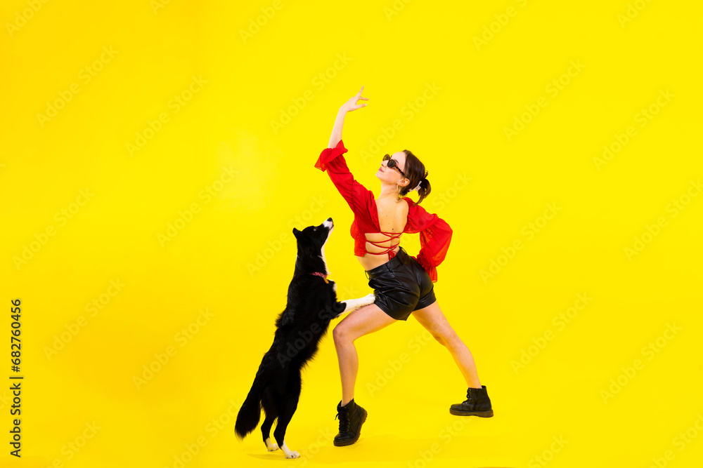 Cute young woman kisses and hugs her puppy border collie dog. Love between owner and dog.