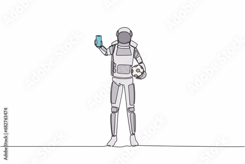 Single continuous line drawing astronaut soccer player holding football ball and smartphone. Mobile football soccer. Mobile sport play match. Cosmonaut deep space. One line design vector illustration
