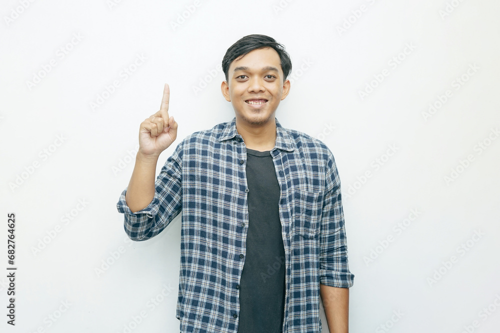 Portrait Indonesian Asian young man with index finger pointing up. Casual concept isolated white background Portrait Indonesian Asian young man with index finger pointing up. Casual concept isolated white background