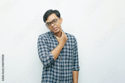Portrait Asian Indonesian young man scratched his neck while grimacing in pain photo