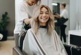 a beautiful blonde model woman in the hairdresser salon gets a new haircut, dyes her hair and style it. sitting on the chair and talks to the hairstylist.