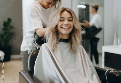 a beautiful blonde model woman in the hairdresser salon gets a new haircut, dyes her hair and style it. sitting on the chair and talks to the hairstylist.