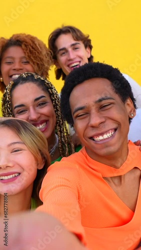 Multi-ethnic and gender people taking a selfie together outdoors next to a yellow urban wall photo