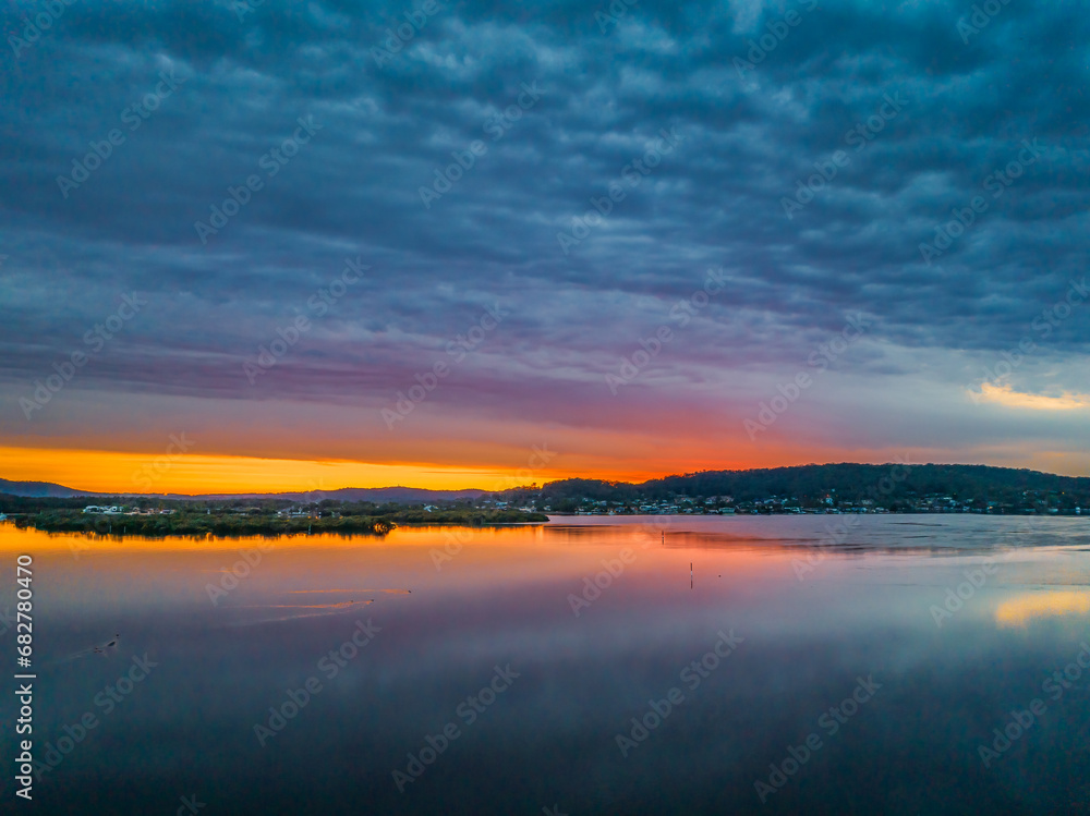 Heavy cloud covered sunrise over the bay with colour and reflections