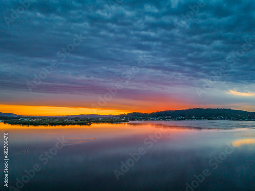 Fototapeta Naklejka Na Ścianę i Meble -  Heavy cloud covered sunrise over the bay with colour and reflections