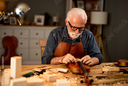 Senior carpenter craftsman making violin instrument © Stockphotodirectors