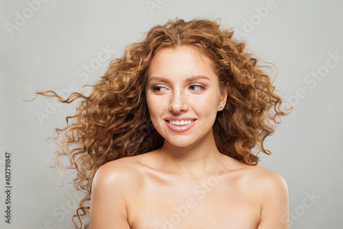 Cheerful young fashion model woman with natural makeup, clear skin and curly hairstyleposing on white background