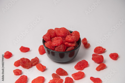 Dried strawberry fruit on white bowl with white background, Dried strawberries scattered on the white background in a black bowl or vessel