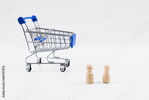 Male and female wooden figure and trolley. Isolated with white background. Shopping conceptual.