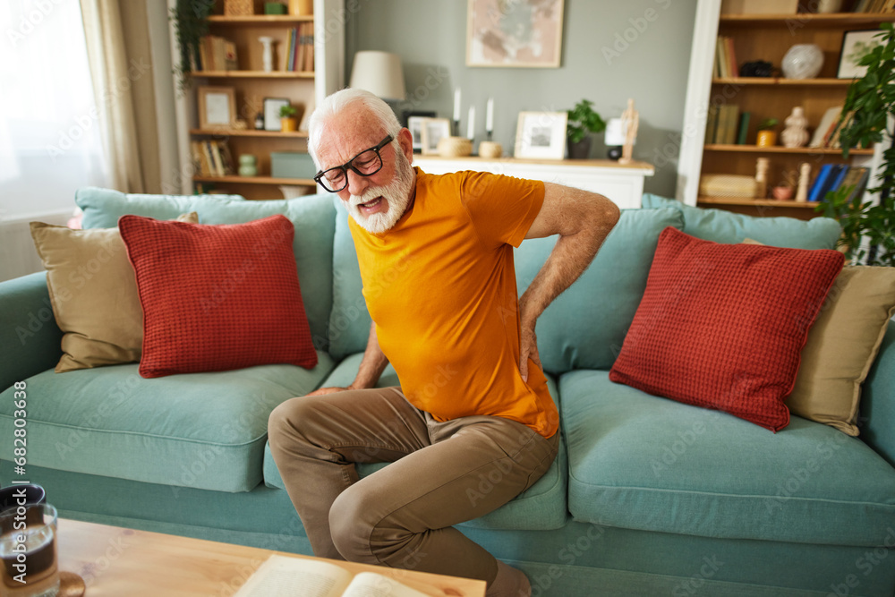 Unhappy senior man suffering from backache at home Unhappy senior man suffering from backache at home