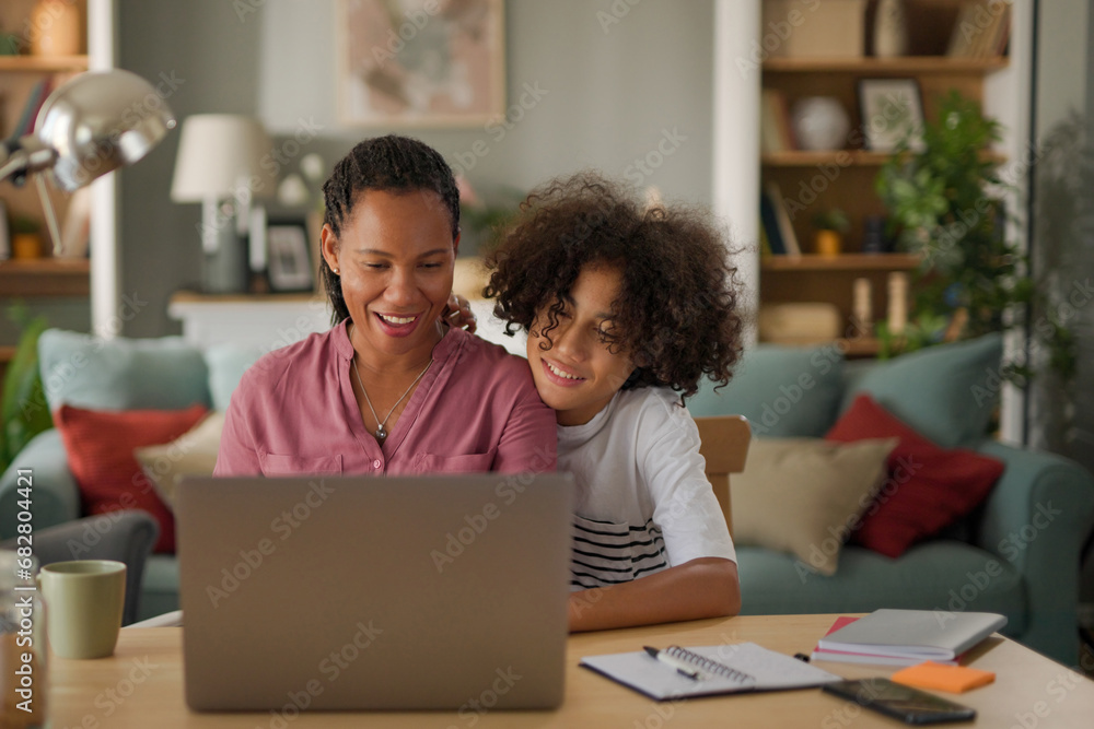 Mother and teenage son using a laptop together at home Mother and teenage son using a laptop together at home