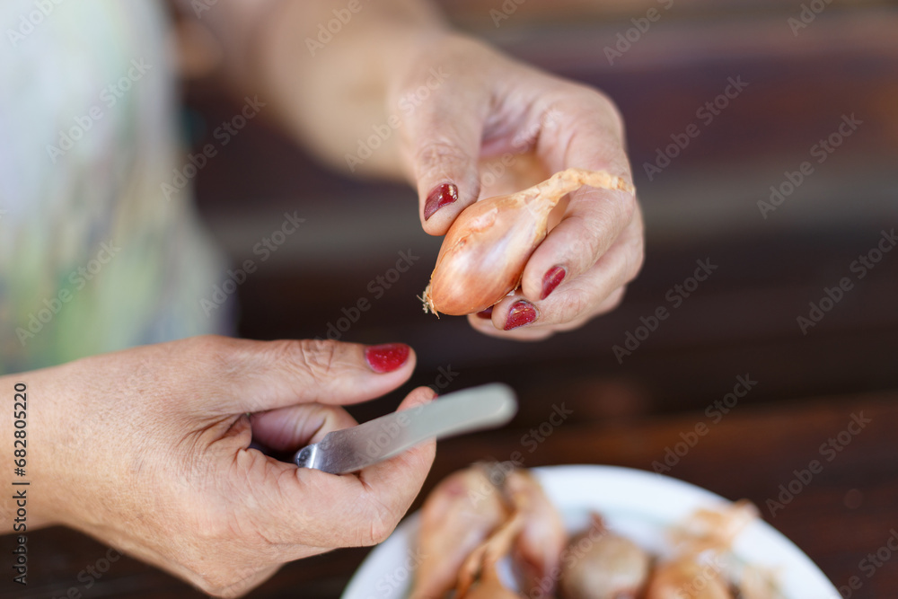 Woman's peeling onion for cooking meal Woman's peeling onion for cooking meal