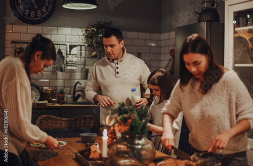 Family preparing festive Christmas Eve dinner together in cozy kitchen decorated for winter holidays