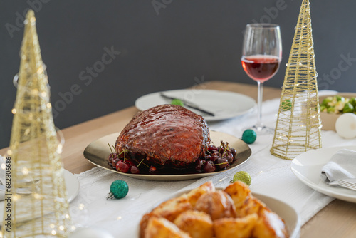 Delicious Christmas ham on wooden table, side angle view with space for text and dark grey background. Christmas dinner setting and decoration with copy space for typography. Beautiful festive season.