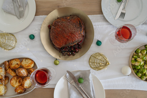 Traditional Sliced Honey Glazed Ham Ready for the Holidays. Christmas meal on table with view from above. Gammon or Ham on plate with potatoes, Brussel sprouts and red wine on table. 