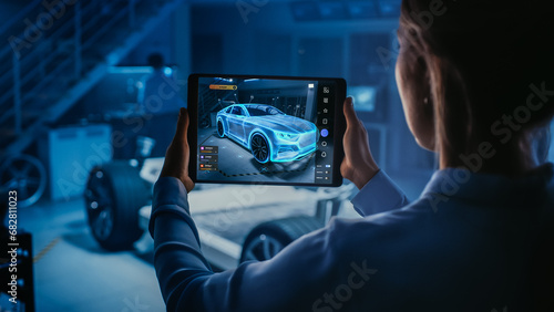 Fotografie Automotive Engineer Working on Electric Car Chassis Platform, Using Tablet with Augmented Reality 3D Software