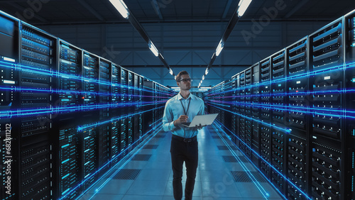 Futuristic Concept: Data Center Chief Technology Officer Holding Laptop, Standing In Warehouse, Information Digitalization Lines Streaming Through Servers. SAAS, Cloud Computing, Web Service photo
