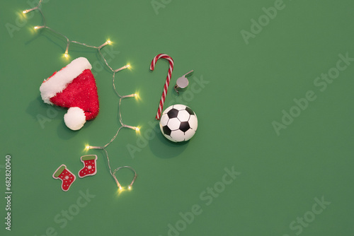 Soccer ball in Christmas Santa hat on a green background like a football field. Christmas in sports
